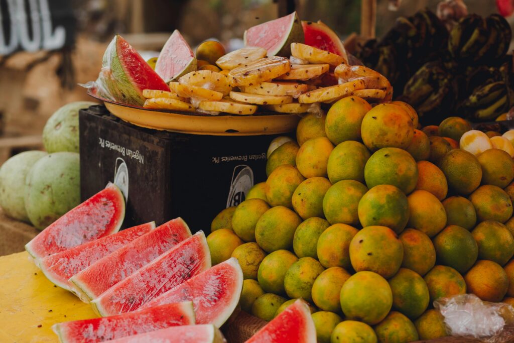 Vibrant slices of watermelon and pineapple with fresh oranges at an outdoor market.